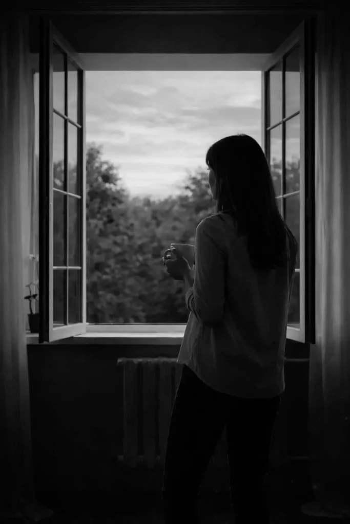 vrouw kijkt uit raam overdenkt relatie scheiding 